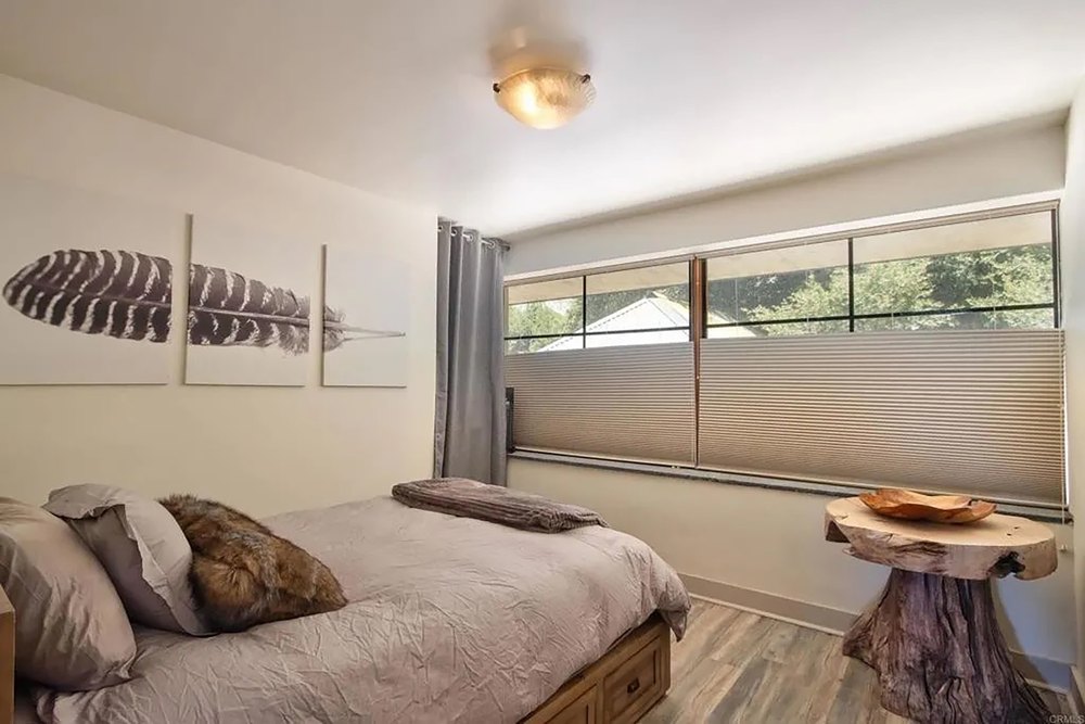 Rustic bedroom with natural wood accent table and warm modern lighting.