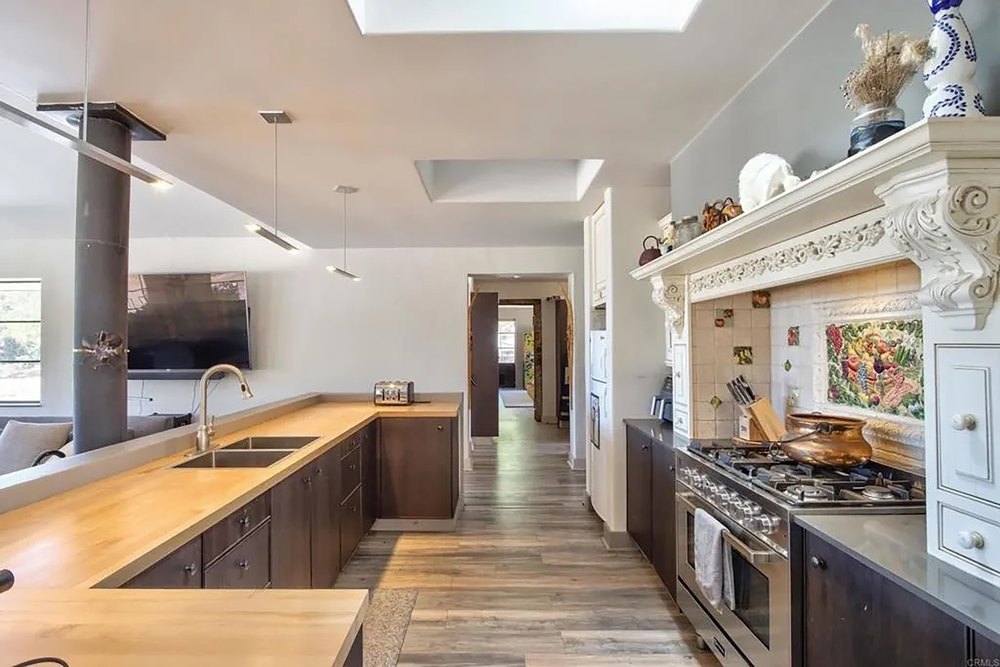 Spacious kitchen with butcher block counter, dark cabinets, and gas range.