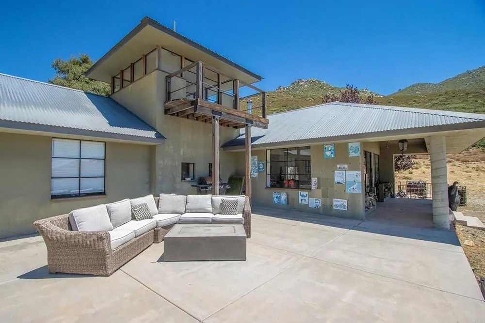Outdoor patio lounge with wicker sectional sofa and fire pit table.