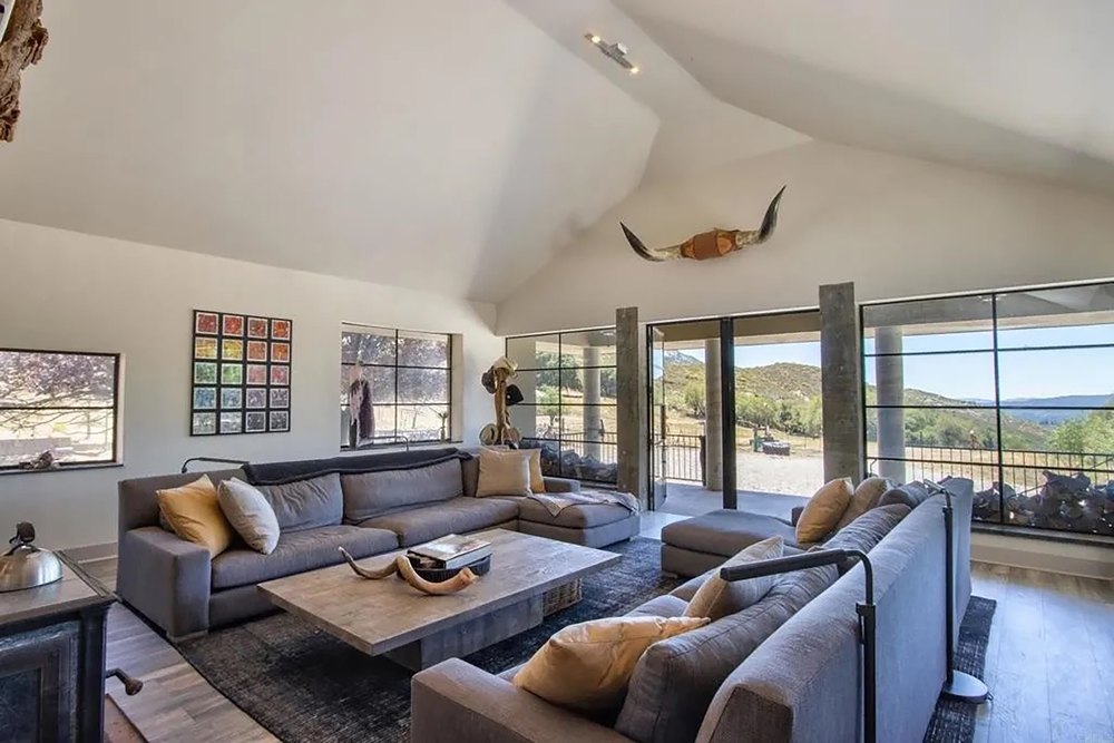 Vaulted ceiling living room with large glass windows and mountain views.